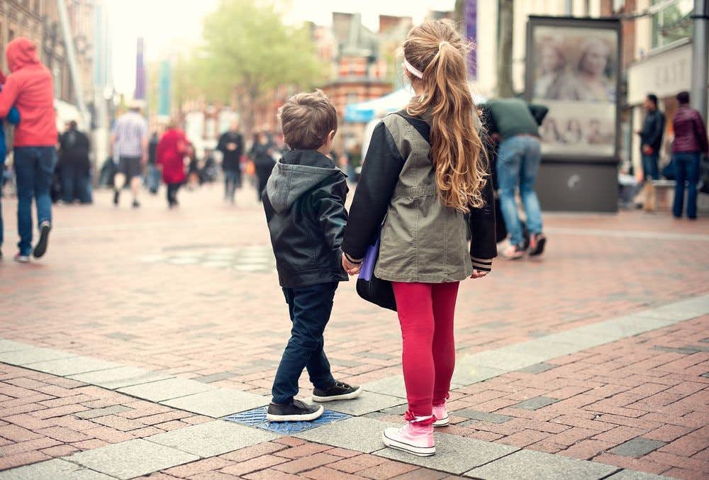 A young boy and girl walking alone in a crowded public square