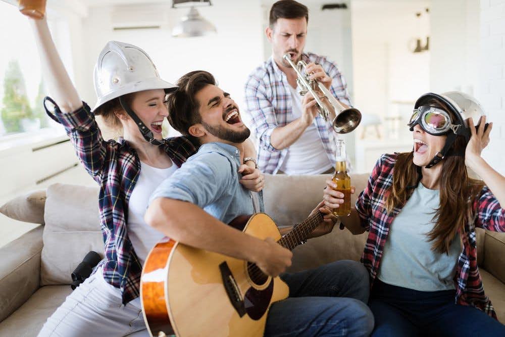 A group of people playing music, drinking been and laughing