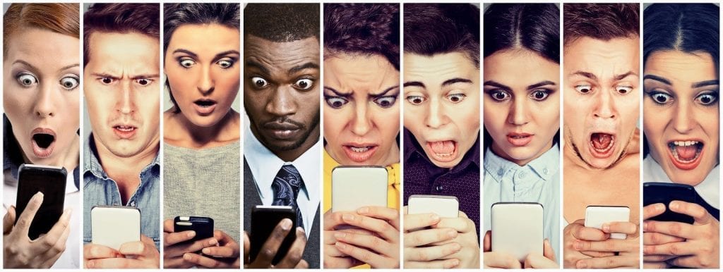 Multicultural group of young people men and women looking shocked at mobile phone