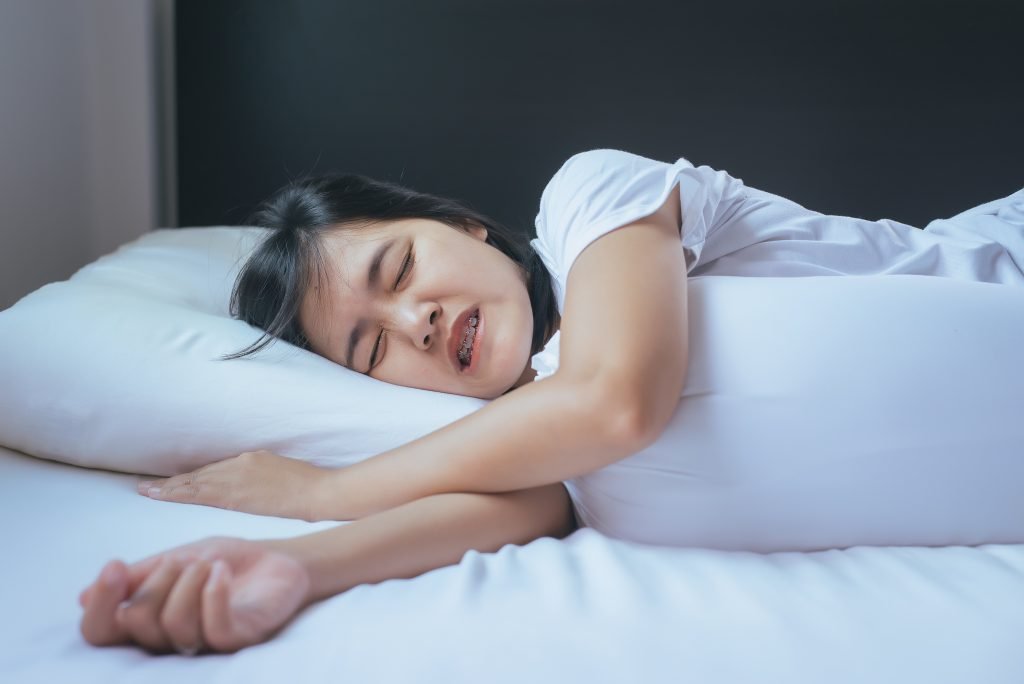 Female sleeping on the bed and grinding teeth,Tiredness and stress
